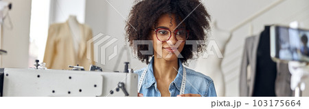 African-American dressmaker holds thread shooting video at workplace in spacious studio 103175664