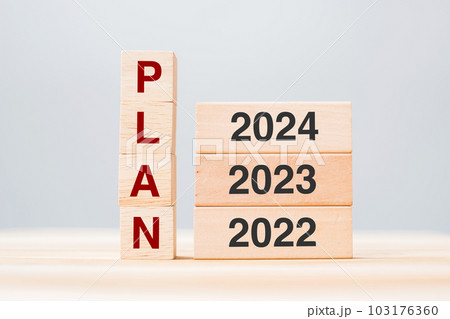 hand pulling 2024 block over 2023 and 2022 wooden building on table background. Business planning, Risk Management, Resolution, strategy, solution, goal, New Year New You and happy holiday concepts 103176360