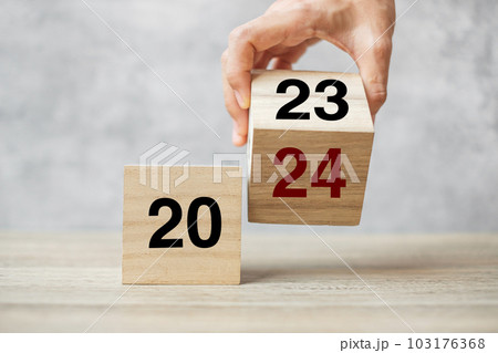 hand flipping block 2023 to 2024 text on table. Resolution, strategy, plan, goal, motivation, reboot, business and New Year holiday concepts 103176368