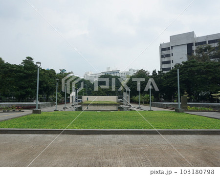 View of people watering the garden yard. This park is surrounded by greenery and several garden lampposts 103180798