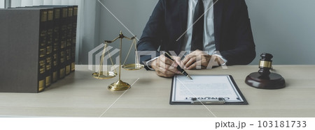 Lawyer hand holding pen and providing legal consult business dispute service at the office with justice scale and gavel hammer 103181733