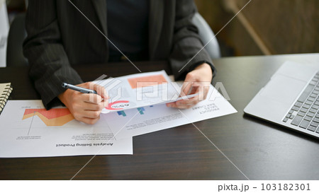 A female executive manager is reviewing business reports at her desk A female executive manager is reviewing business reports at her desk 103182301