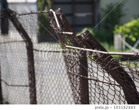 ひしゃげて曲がった古い金網フェンス ひしゃげて曲がった古い金網フェンス 103182883