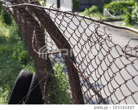 錆びた古い金網フェンスと古タイヤ 103182887