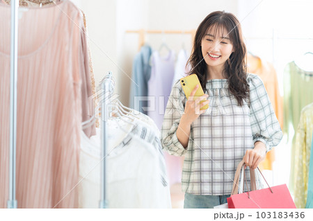 ショッピングセンターでショッピングしながらスマホを操作する若い女性 ショッピングセンターでショッピングしながらスマホを操作する若い女性 103183436