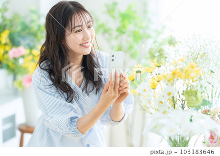 フラワーショップでスマホで撮影をする若い女性の店員 フラワーショップでスマホで撮影をする若い女性の店員 103183646