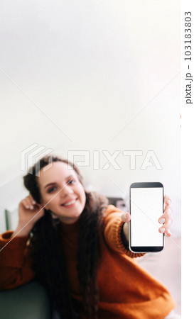 Happy young woman holding mobile phone to showcase blank display for app advertising. Smartphone 103183803