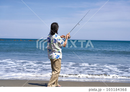 晴れた日の海辺で釣りをする長髪男性の後ろ姿 103184368