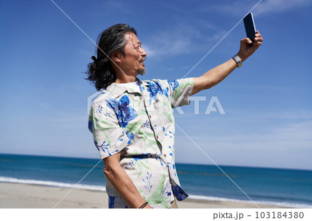 晴れた日の海辺で自撮りをするミドルシニア男性 晴れた日の海辺で自撮りをするミドルシニア男性 103184380