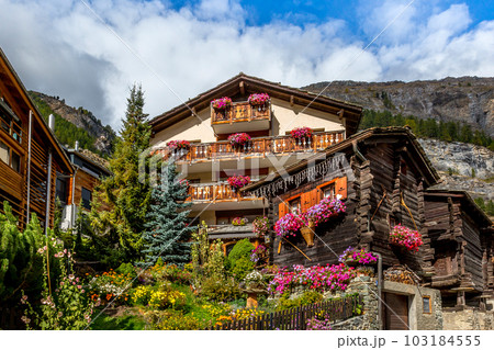 Traditional wooden alpine chalet with flowers 103184555