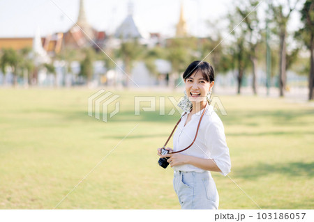 Portrait of asian woman traveler using camera. Asia summer tourism vacation concept with the grand palace in a background at Bangkok, Thailand Portrait of asian woman traveler using camera. Asia summer tourism vacation concept with the grand palace in a background at Bangkok, Thailand 103186057