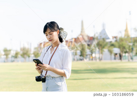 Portrait beautiful young asian woman with smartphone on summer holiday vacation trip with the grand palace in a background at Bangkok, Thailand Portrait beautiful young asian woman with smartphone on summer holiday vacation trip with the grand palace in a background at Bangkok, Thailand 103186059