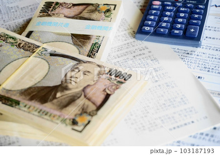 資料の上に積み上げられた一万円札と電卓 資料の上に積み上げられた一万円札と電卓 103187193