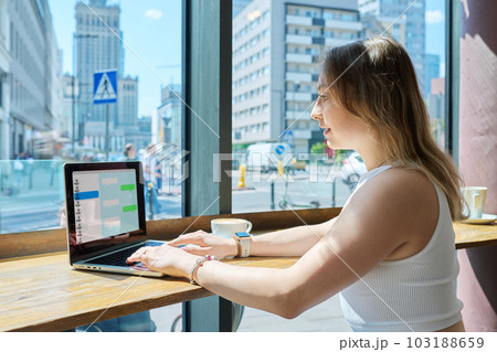 Young female college student sitting in cafe texting in chat with friends Young female college student sitting in cafe texting in chat with friends 103188659