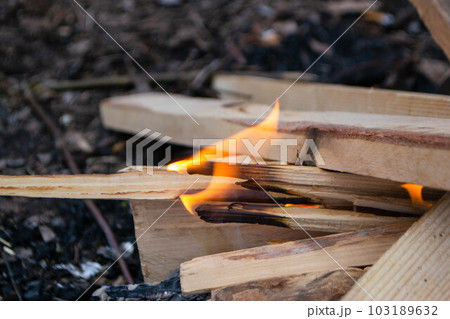 A fire burns in a campfire with a red fire in the background. 103189632