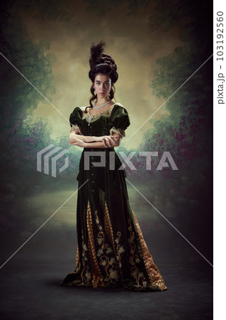 Full-length portrait of beautiful young girl, princess, royal person in elegant dress sanding against dark vintage background Full-length portrait of beautiful young girl, princess, royal person in elegant dress sanding against dark vintage background 103192560