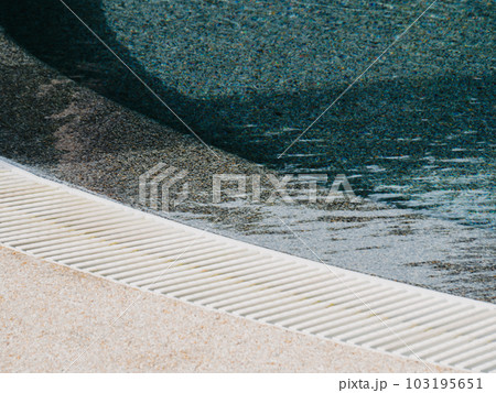 View of round swimming pool side with clear blue water with sunlight shadow wave reflections 103195651