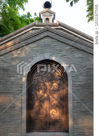 Antique iron arched door on brick stone wall in a historic brick building. Antique iron arched door on brick stone wall in a historic brick building. 103197508