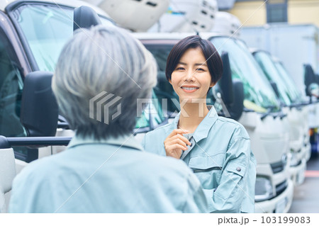 トラックの前で打ち合わせする作業員の女性 トラックの前で打ち合わせする作業員の女性 103199083