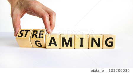 Gaming and streaming symbol. Businessman turns wooden cubes and changes the word gaming to streaming. Beautiful white table white background, copy space. Business, gaming and streaming concept. Gaming and streaming symbol. Businessman turns wooden cubes and changes the word gaming to streaming. Beautiful white table white background, copy space. Business, gaming and streaming concept. 103200036