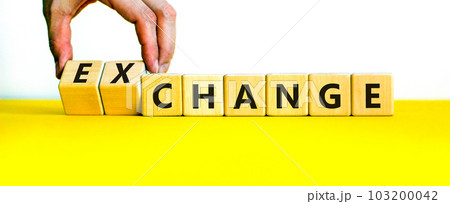 Change or exchange symbol. Businessman turns wooden cubes and changes the word change to exchange. Beautiful yellow table, white background, copy space. Business and change or exchange concept. 103200042