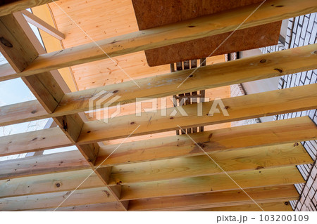 In new custom home deck patio floor joists are being laid out in new manner for wooden deck 103200109