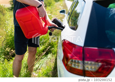 The car parked on the side of the road, the driver refuels the car from the canister. Help on the road. Lack of fuel - oil, diesel, gasoline. 103200152