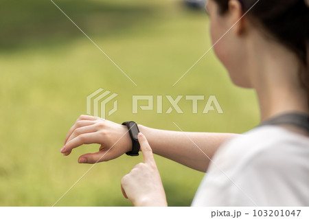 Young woman checks her smart watch. Close up of hand with device. The concept of a modern device and wellness Young woman checks her smart watch. Close up of hand with device. The concept of a modern device and wellness 103201047