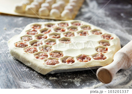 Dumplings preparation process on the table with dough, rolling pin  103201337