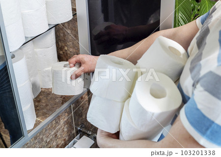 A man is stocking up toilet paper at home. A man is stocking up toilet paper at home. 103201338