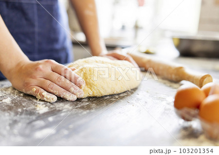 Female hands making dough for baking on wooden table 103201354
