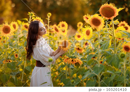 Beautiful woman in a dress in a field of sunflowers 103201410