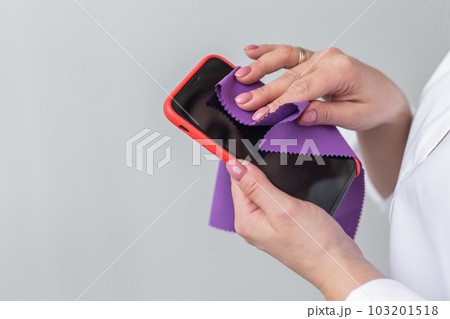 Germs elimination. Cleaning the smartphone screen with fiber cloth from dirt dust and other external factors. Mobile Care Concept Germs elimination. Cleaning the smartphone screen with fiber cloth from dirt dust and other external factors. Mobile Care Concept 103201518