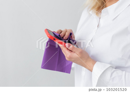 Germs elimination. Cleaning the smartphone screen with fiber cloth from dirt dust and other external factors. Mobile Care Concept Germs elimination. Cleaning the smartphone screen with fiber cloth from dirt dust and other external factors. Mobile Care Concept 103201520