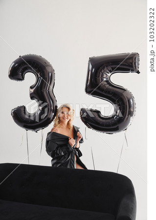 a naked blonde with tattoos in a black coat by a black sofa. birthday a naked blonde with tattoos in a black coat by a black sofa. birthday 103202322