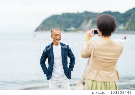海辺で写真を撮るミドル夫婦 103205442