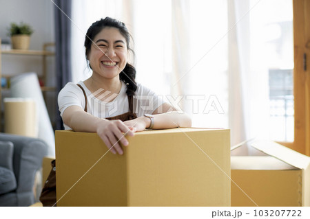 Happy woman smiling at home during move with boxes Happy woman smiling at home during move with boxes 103207722
