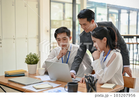 A male boss discusses work, gives advice, and checks a new project on a laptop A male boss discusses work, gives advice, and checks a new project on a laptop 103207956