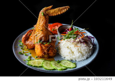 Roasted chicken wing in Vietnamese style with rice, vegetables and sauce isolated on black background side view 103211649