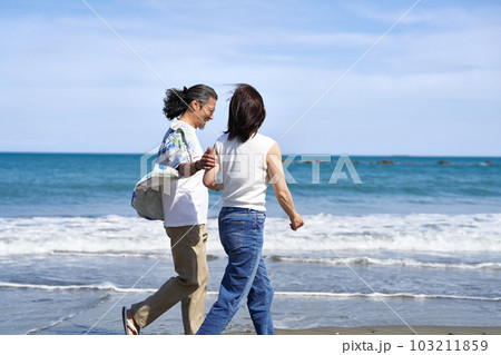 笑顔で海辺を歩くミドルシニアの男女 103211859