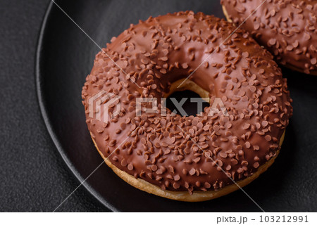 Delicious chocolate glazed donut sprinkled with chocolate chips Delicious chocolate glazed donut sprinkled with chocolate chips 103212991