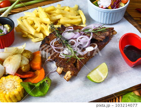 Grilled smoked pork ribs with french fries and soy sauce and salad on wooden board 103214077