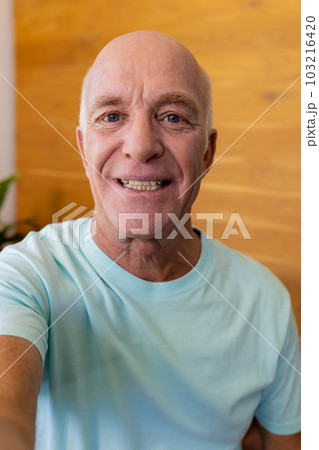 Happy senior caucasian man making video call smiling at home 103216420