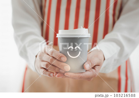 closeup woman wearing apron holding paper cup of hot coffee 103216588