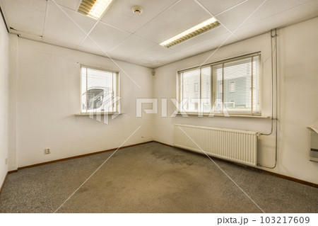 an empty room with white walls and grey carpet on the floor, there is a window that has blinds in it an empty room with white walls and grey carpet on the floor, there is a window that has blinds in it 103217609