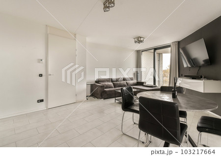 a living room with black and white furniture on the floor in front of a large flat screen tv mounted to the wall 103217664
