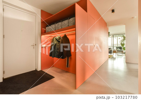 a walk in closet with clothes hanging on the wall and an open door that leads to another room where there is a coat rack 103217780