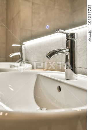 a bathroom sink with two faucets on the counter top and one faucet in the wall behind it a bathroom sink with two faucets on the counter top and one faucet in the wall behind it 103217782