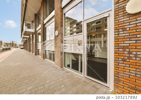 the outside of a building with brick walls and glass doors on both sides, looking out onto an empty street the outside of a building with brick walls and glass doors on both sides, looking out onto an empty street 103217892