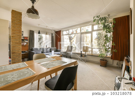 a living room with couches, chairs and a table in the middle of the room there is a plant hanging on the wall 103218078